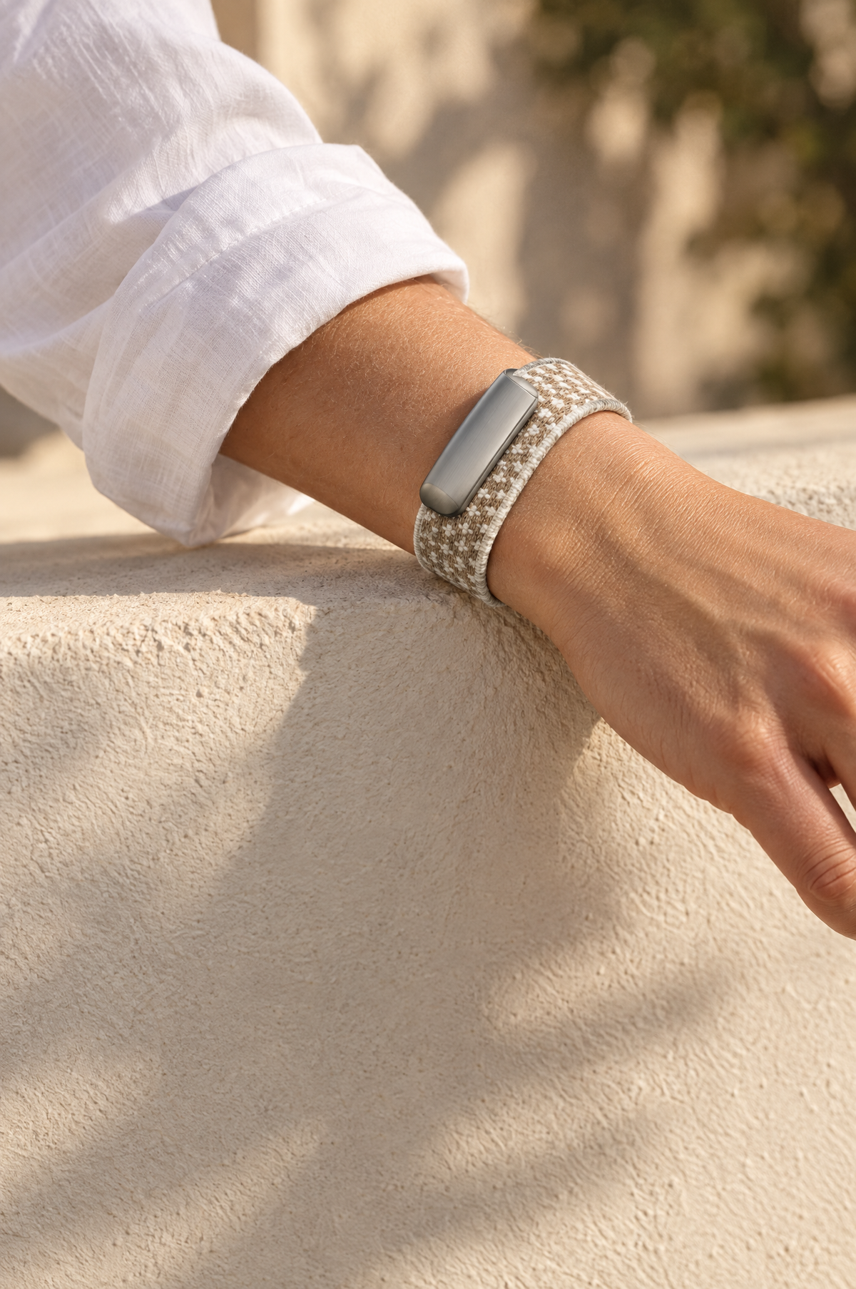 Bone knit band on a wrist resting on a sunlit wall